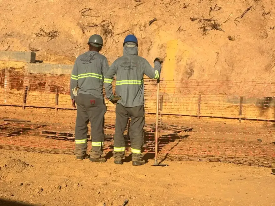Profissionais com EPIs próximos à área escavada de uma obra